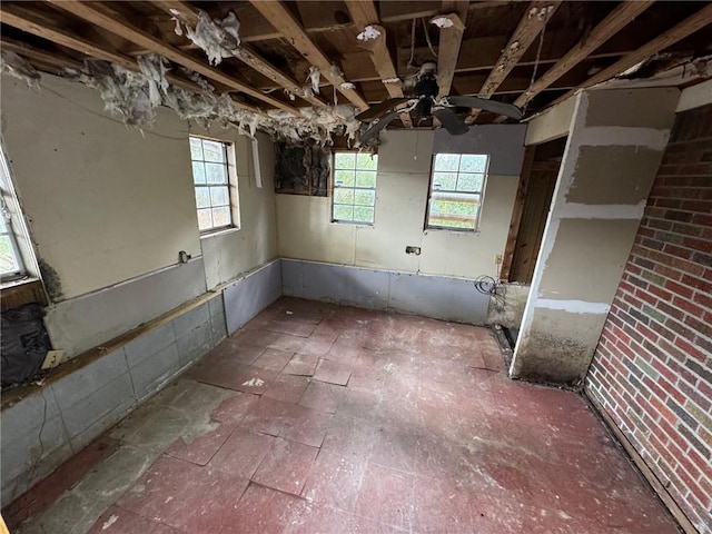 basement with ceiling fan and a healthy amount of sunlight