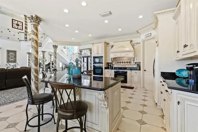 kitchen featuring custom exhaust hood, a breakfast bar, dark countertops, decorative columns, and black appliances
