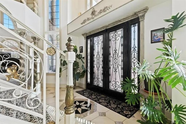 tiled foyer entrance featuring baseboards, a high ceiling, and french doors