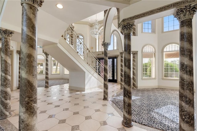 entrance foyer featuring crown molding, baseboards, and ornate columns