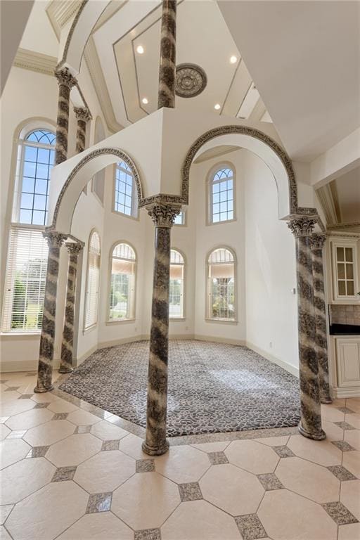 entrance foyer featuring decorative columns, baseboards, and a high ceiling