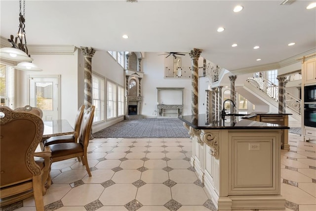 kitchen with a ceiling fan, cream cabinetry, a sink, and a fireplace