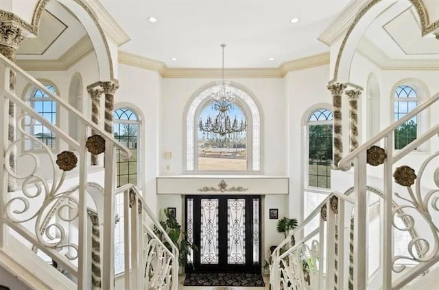 foyer with a towering ceiling, a notable chandelier, and crown molding