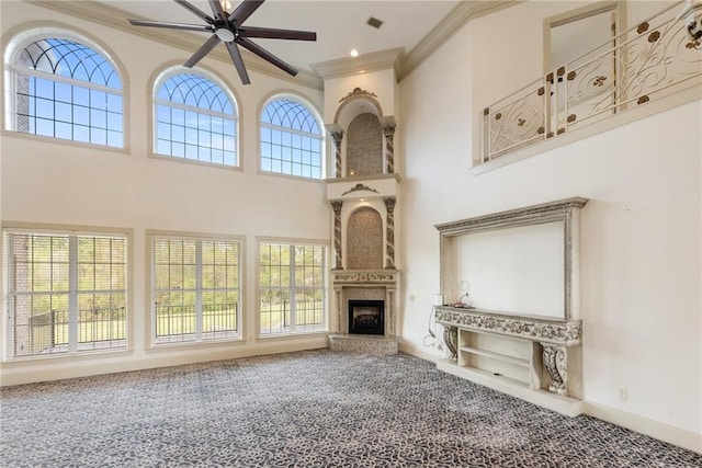 unfurnished living room featuring plenty of natural light, ornamental molding, carpet flooring, and a ceiling fan