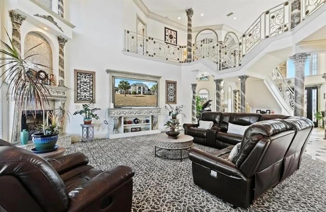 living area featuring ornate columns, a high ceiling, a healthy amount of sunlight, and a premium fireplace