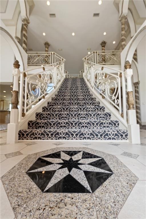 stairs featuring marble finish floor, visible vents, arched walkways, and recessed lighting