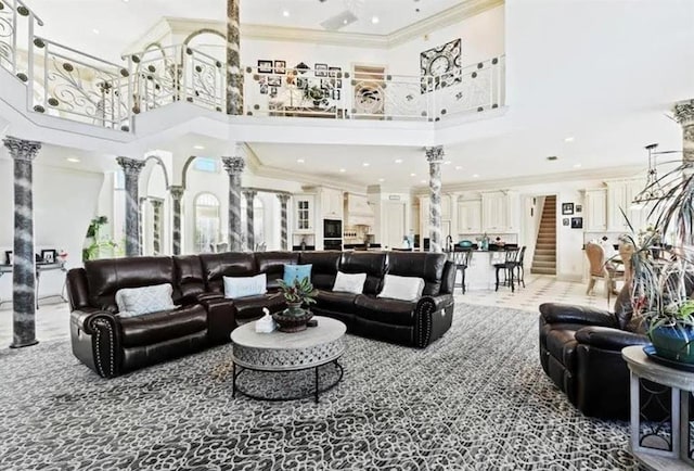 living room featuring a high ceiling, ornamental molding, and ornate columns