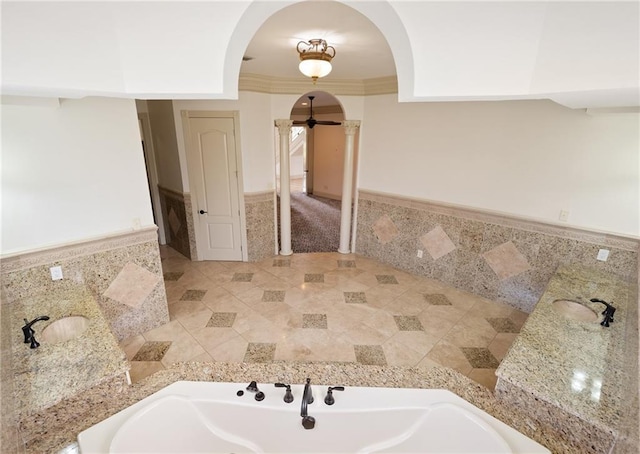 bathroom featuring decorative columns, a wainscoted wall, ornamental molding, and tile walls