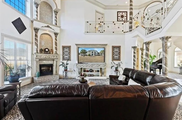 living area featuring decorative columns, a towering ceiling, crown molding, and a fireplace