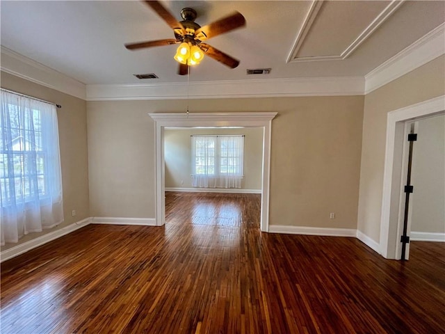 empty room featuring a healthy amount of sunlight, crown molding, visible vents, and wood finished floors