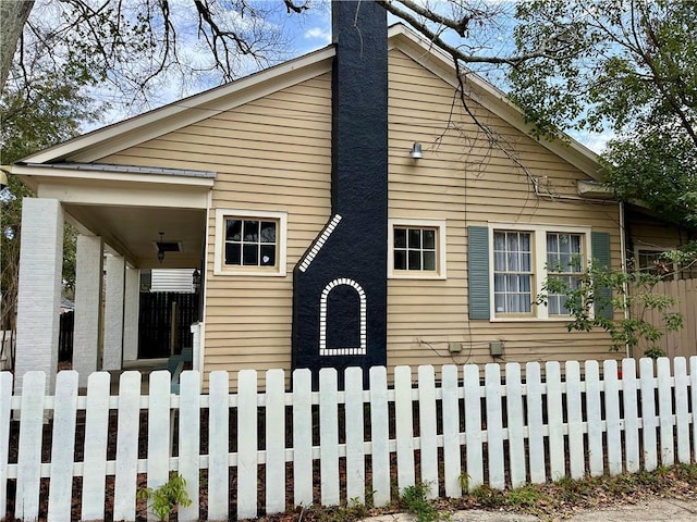 view of side of home featuring a fenced front yard and a chimney