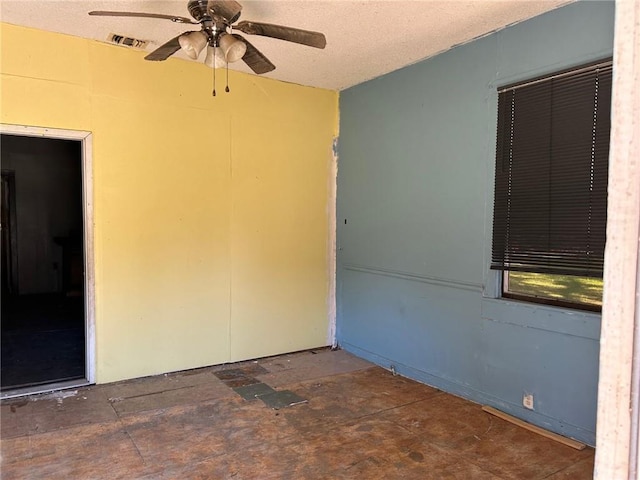 unfurnished room with ceiling fan and a textured ceiling