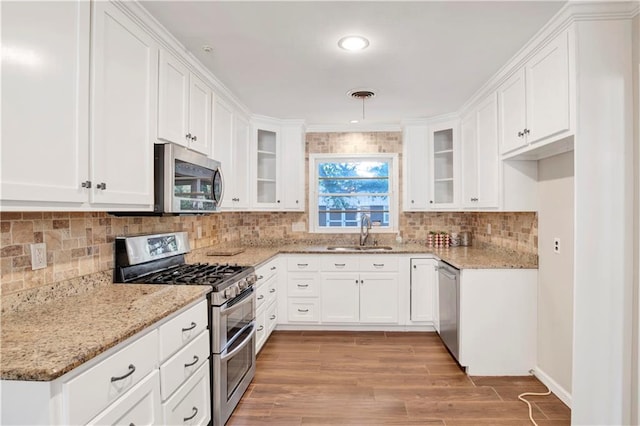 kitchen with sink, light wood-type flooring, stainless steel appliances, white cabinets, and light stone counters