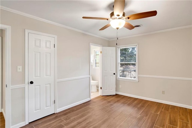 unfurnished bedroom with a closet, ensuite bath, hardwood / wood-style floors, crown molding, and ceiling fan