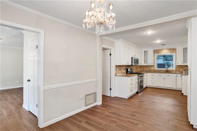 kitchen with white cabinets, light wood-type flooring, crown molding, decorative light fixtures, and stainless steel appliances