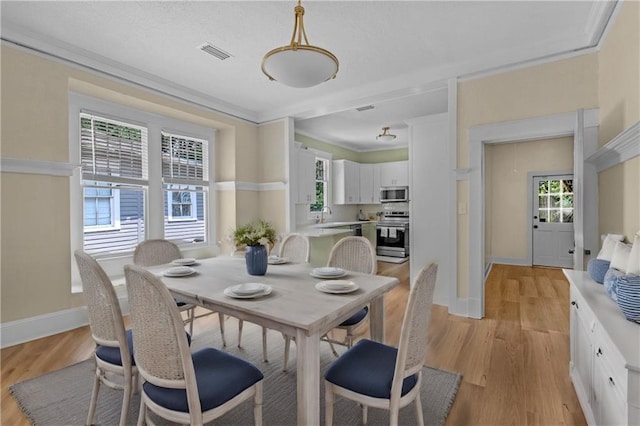 dining area featuring crown molding, visible vents, light wood-style flooring, and baseboards