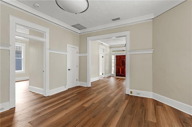 unfurnished room featuring a wealth of natural light, wood finished floors, and ornamental molding