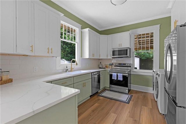 kitchen featuring a sink, stainless steel appliances, independent washer and dryer, light wood-type flooring, and white cabinets
