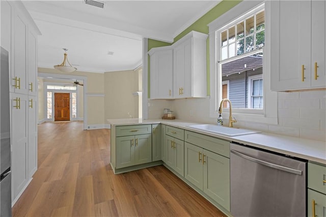 kitchen featuring green cabinets, a sink, crown molding, and stainless steel dishwasher