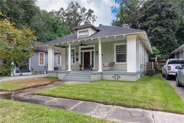bungalow-style house with covered porch, central air condition unit, ceiling fan, a front lawn, and a chimney