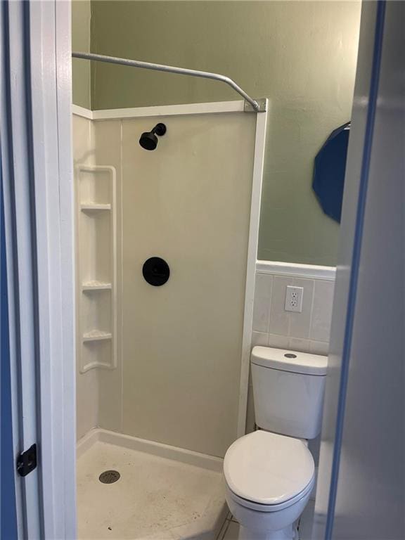 full bath with a wainscoted wall, toilet, tile walls, and a shower stall