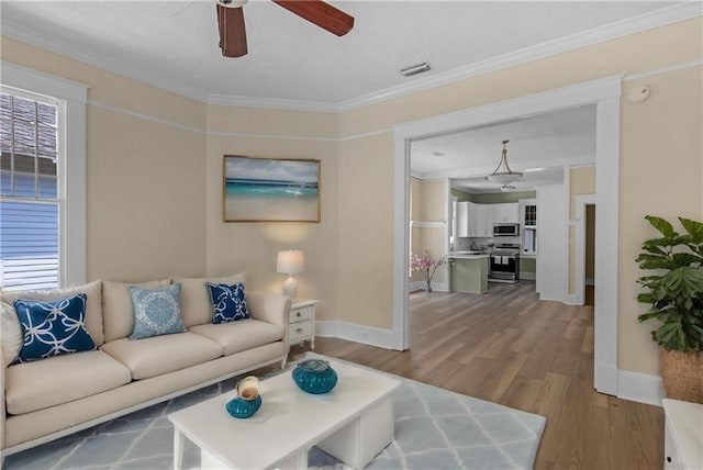 living area with ceiling fan, baseboards, visible vents, and wood finished floors
