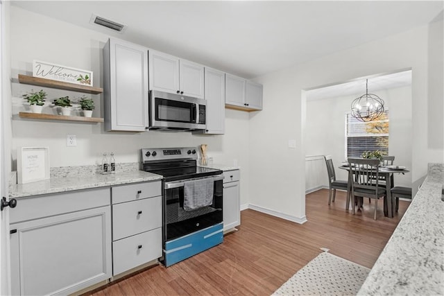 kitchen with hanging light fixtures, a notable chandelier, light hardwood / wood-style floors, light stone counters, and stainless steel appliances