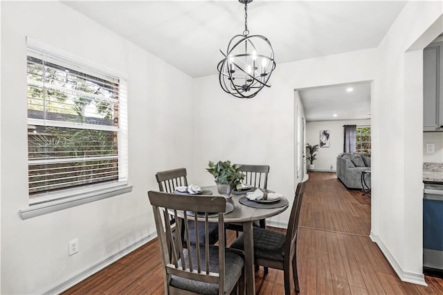 dining area featuring a wealth of natural light, dark hardwood / wood-style flooring, and an inviting chandelier