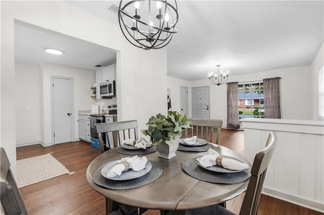 dining room with dark hardwood / wood-style floors and a notable chandelier