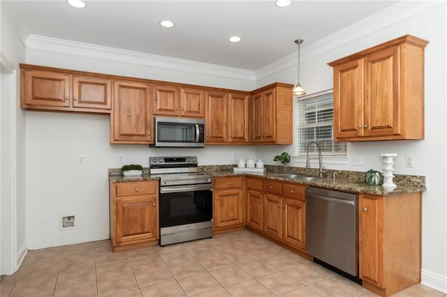 kitchen featuring brown cabinetry, a sink, ornamental molding, stainless steel appliances, and decorative light fixtures