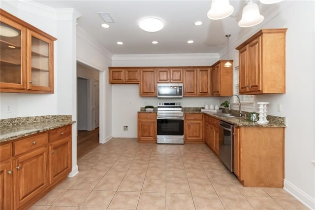 kitchen featuring a sink, dark stone counters, appliances with stainless steel finishes, and brown cabinetry