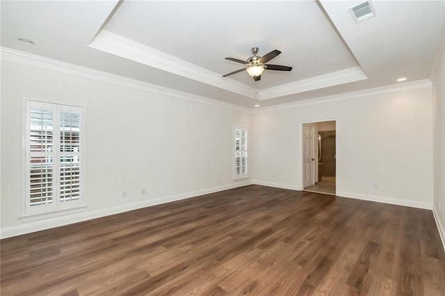 spare room with a tray ceiling, plenty of natural light, and wood finished floors