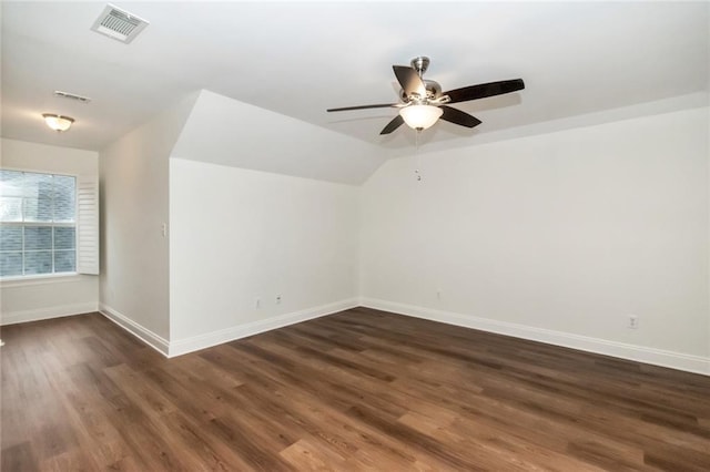 additional living space with visible vents, baseboards, dark wood-style floors, and vaulted ceiling