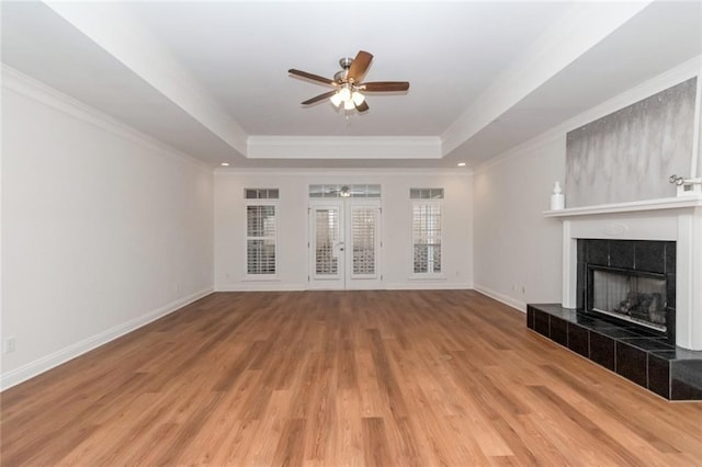 unfurnished living room featuring baseboards, a raised ceiling, ceiling fan, and a tile fireplace