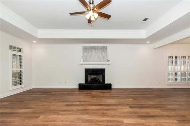 unfurnished living room featuring a tiled fireplace, plenty of natural light, and a raised ceiling