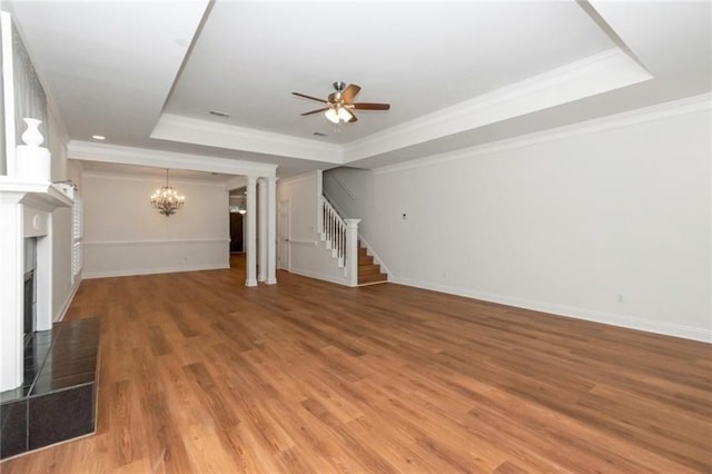 unfurnished living room with light wood-style flooring, a fireplace with raised hearth, ceiling fan with notable chandelier, a raised ceiling, and stairs