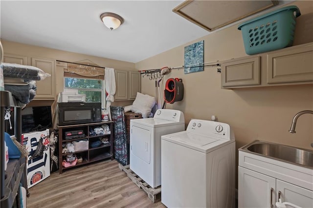 washroom with light wood-type flooring, sink, washer and clothes dryer, and cabinets