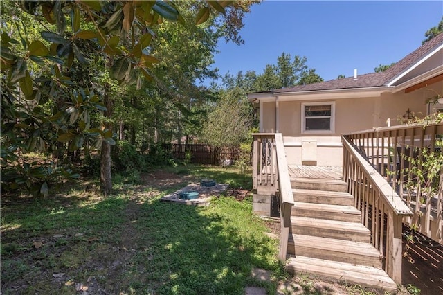 view of exterior entry with a deck and a lawn