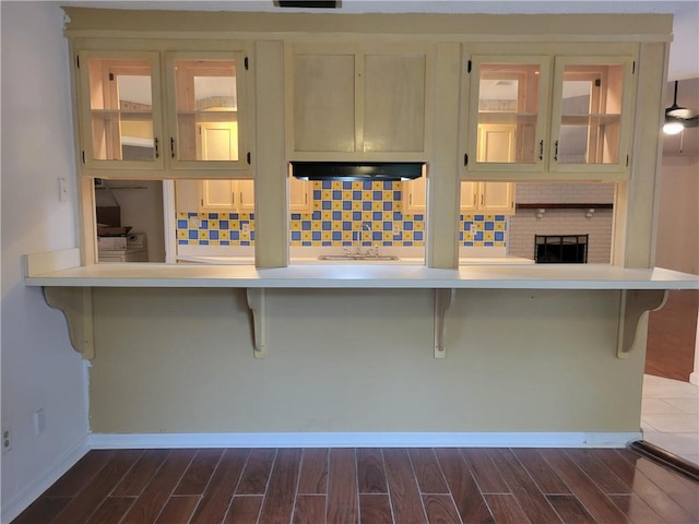 2544 Buckboard Ct, Mobile, AL 36695 - kitchen featuring dark wood-style flooring, cooktop, under cabinet range hood, and glass insert cabinets