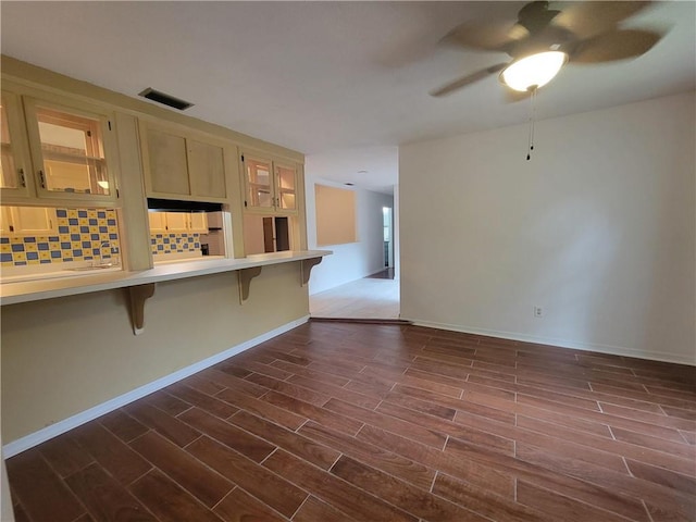 2544 Buckboard Ct, Mobile, AL 36695 - kitchen with a kitchen bar, ceiling fan, light countertops, decorative backsplash, and dark wood-style floors