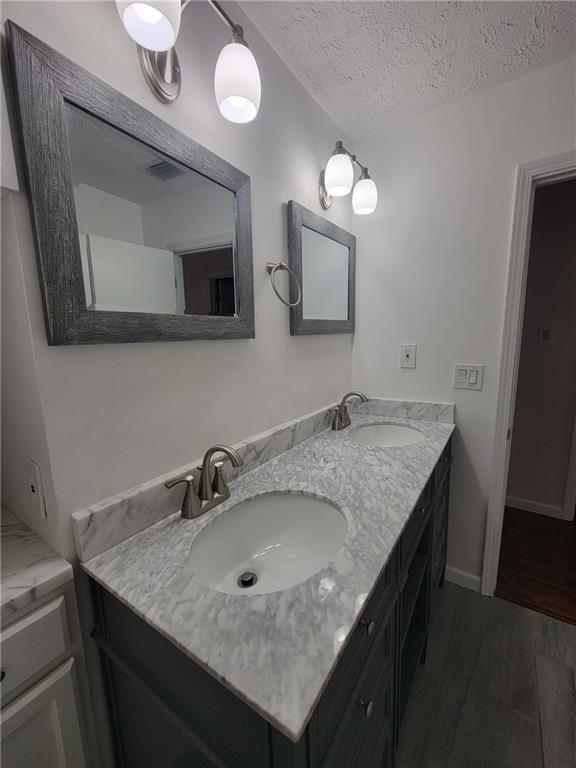 2544 Buckboard Ct, Mobile, AL 36695 - bathroom with wood finished floors, double vanity, and a textured ceiling