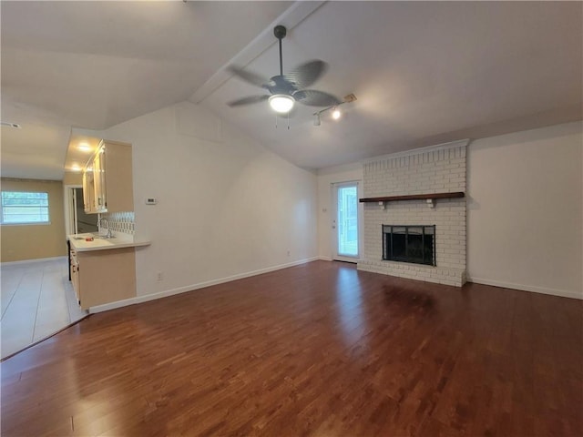 2544 Buckboard Ct, Mobile, AL 36695 - unfurnished living room with wood finished floors, healthy amount of natural light, a ceiling fan, vaulted ceiling, and a brick fireplace