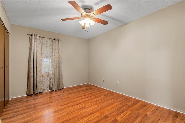 spare room featuring a textured ceiling, light wood-type flooring, and ceiling fan