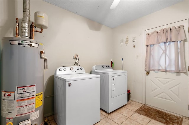 clothes washing area featuring washer and dryer, light tile patterned floors, and water heater