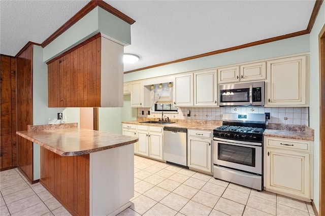 kitchen with kitchen peninsula, appliances with stainless steel finishes, sink, light tile patterned floors, and cream cabinetry