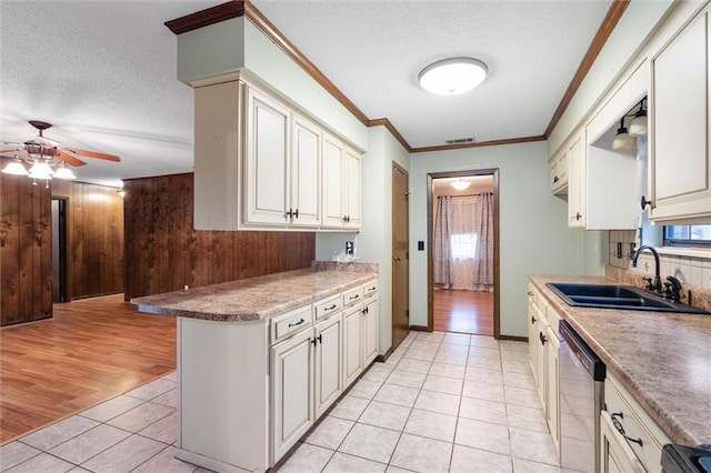 kitchen with sink, wooden walls, stainless steel dishwasher, a textured ceiling, and light hardwood / wood-style floors