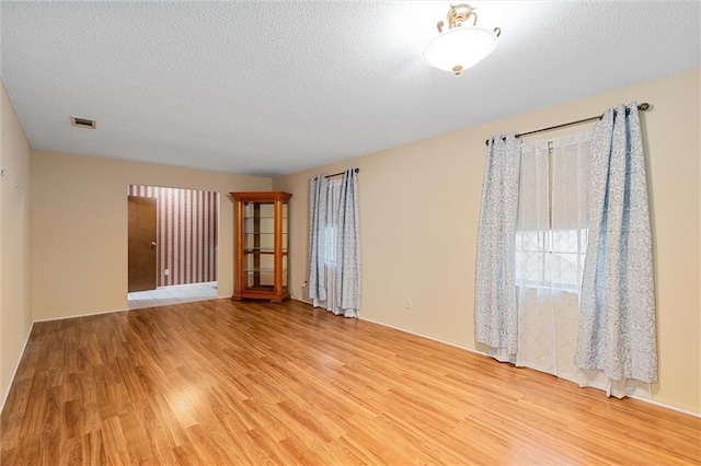 empty room featuring a textured ceiling and light wood-type flooring