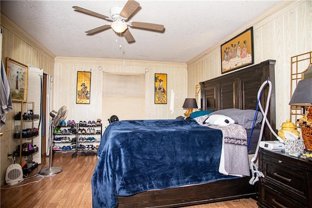 612 Summerland Dr, Mobile, AL 36617 - bedroom with ornamental molding, wood finished floors, wood walls, a textured ceiling, and a ceiling fan