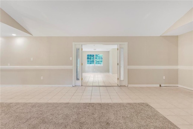 empty room with baseboards, tile patterned floors, and vaulted ceiling