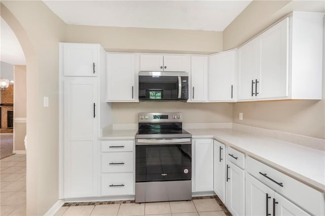 kitchen with light countertops, arched walkways, white cabinets, and stainless steel appliances